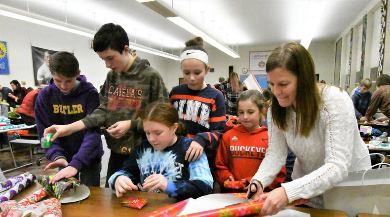 Megan Reinhart, right, helps young people, including students from Morton Middle School in Vandalia, wrap during the Project Believe Wrap Party in Tipp City. CONTRIBUTED.
