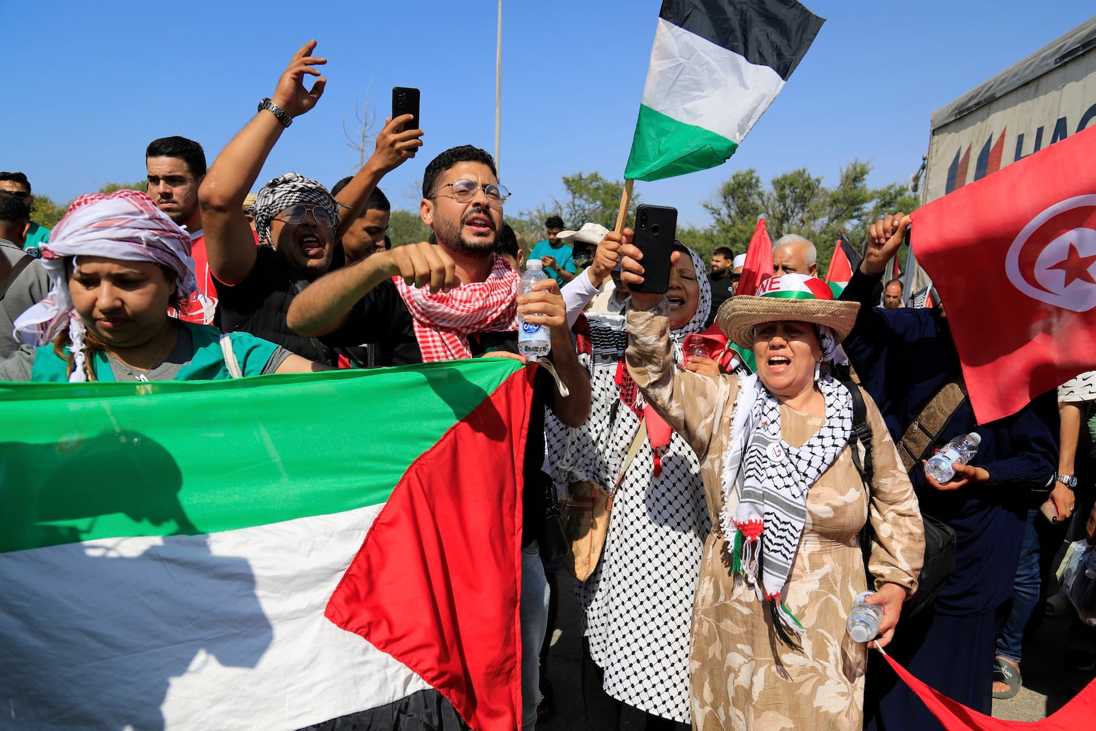 Members of a humanitarian convoy of at least 1,500 people, including activists and supporters from Algeria and Tunisia, shout pro-Palestinian slogans as they gather, on their way to Gaza via Egypt's Rafah Crossing, in Zawiya, Libya, Tuesday, June 10, 2025. (AP Photo/Yousef Murad)
