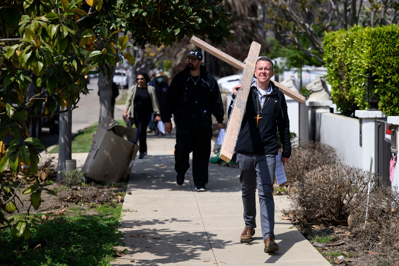 Pastor John Shaver, right, carries a cross during a Cross Walk event by the Community United Methodist Church of the Pacific Palisades, Friday, April 18, 2025, in the Pacific Palisades area of Los Angeles. (AP Photo/William Liang)
