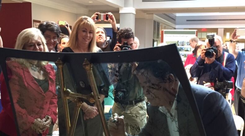 Fuyao Group Chairman Cao DeWang sings the first windshield made in the company’s Moraine plant at Carillon Historical Park in the summer of 2015. THOMAS GNAU/STAFF