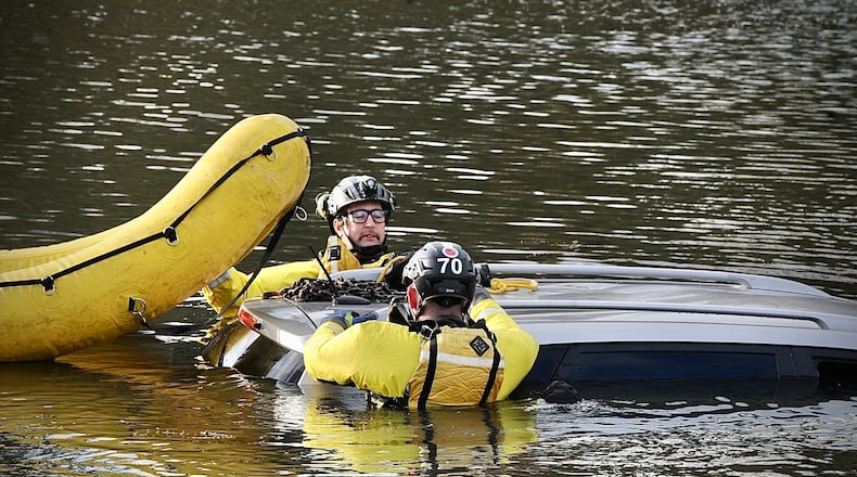 Members of the Beavercreek Twp. Fire Department hook up a car to be towed from the water on Lakeview Drive in Beavercreek. The woman driving the car was rescued by the fire department after he was aided by a good Samaritan. MARSHALL GORBY\STAFF