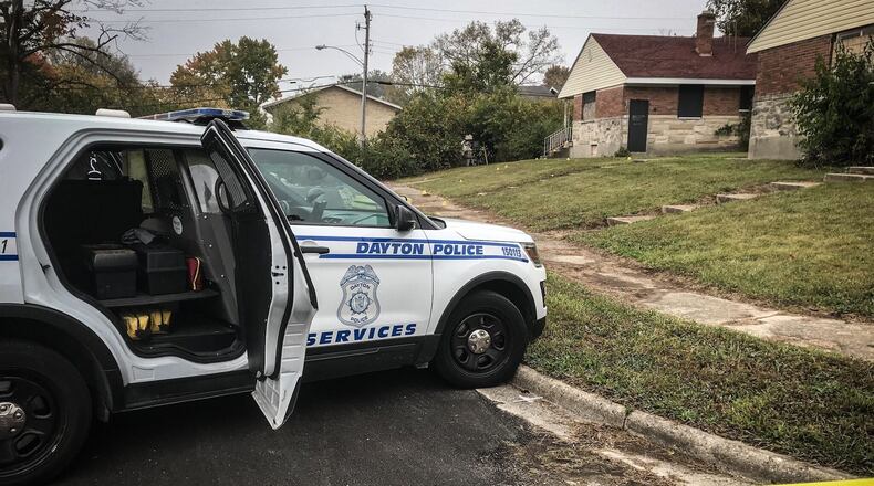 Multiple evidence markers are in the street and lead up to a house with boarded-up windows near Stanford Place and Harold Drive in Dayton Monday morning. A person is dead after a 911 caller reported a bloody person had been found. JIM NOELKER/STAFF