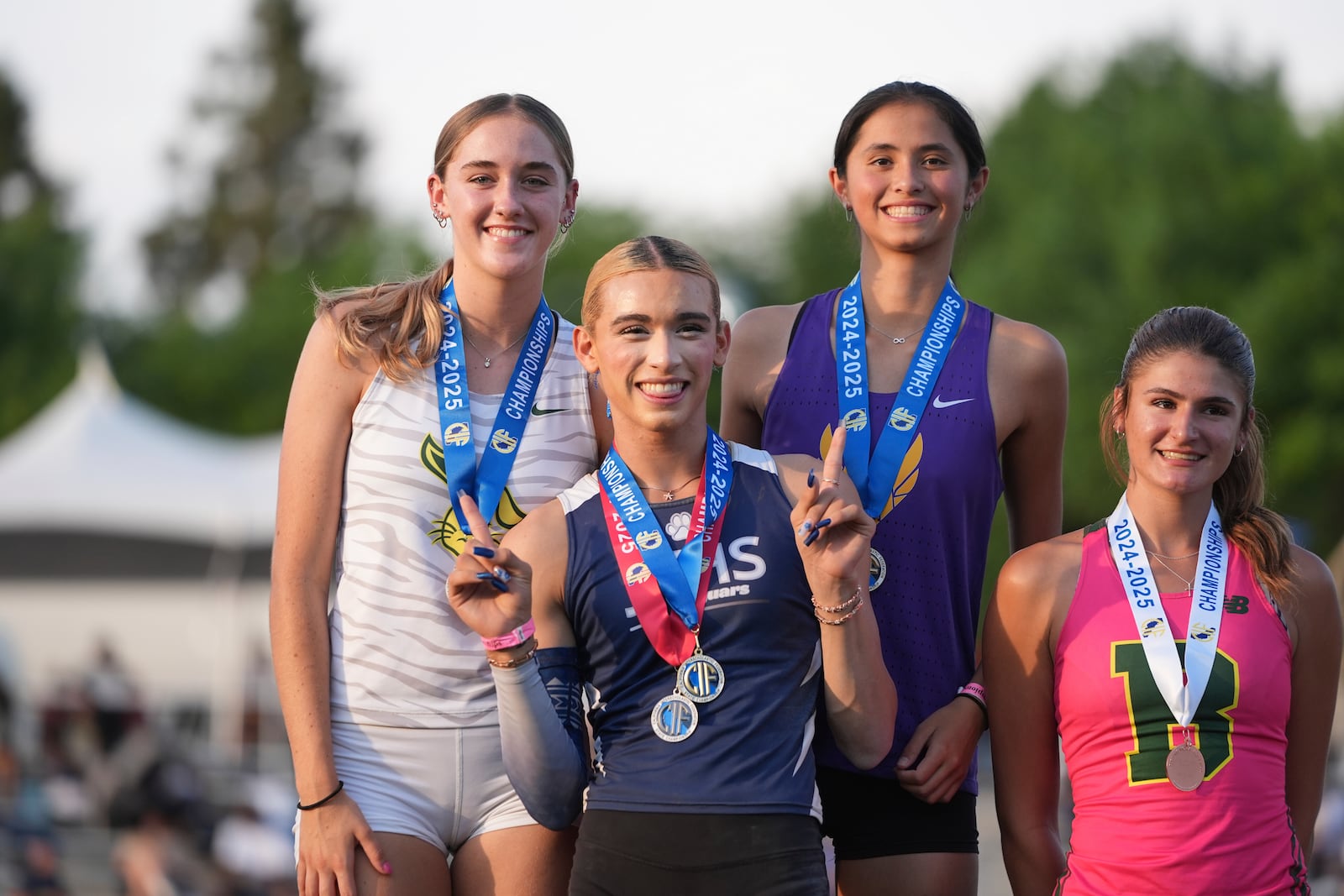 AB Hernandez, center, flashes a sign as she shares the first-place spot on the podium with Jillene Wetteland, left, and Lelani Laruelle during a medal ceremony for the high jump at the California high school track-and-field championships in Clovis, Calif., Saturday, May 31, 2025. At right is third-place finisher Julia Teven. (AP Photo/Jae C. Hong)