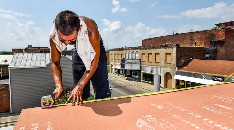 Leo Felix, with C&J Roofing, cuts underlayment while he and the crew try to stay cool as they replace rubber roofing on a building on Central Avenue Tuesday, July 18, in Middletown. NICK GRAHAM/STAFF