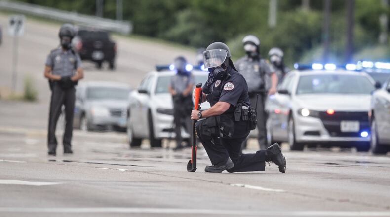 Cheers erupted after one officer took a knee. Two minutes later, a second officer took a knee, and, shortly after, three more Beavercreek officers took a knee. Other officers dropped their shields on the pavement. JIM NOELKER/STAFF
