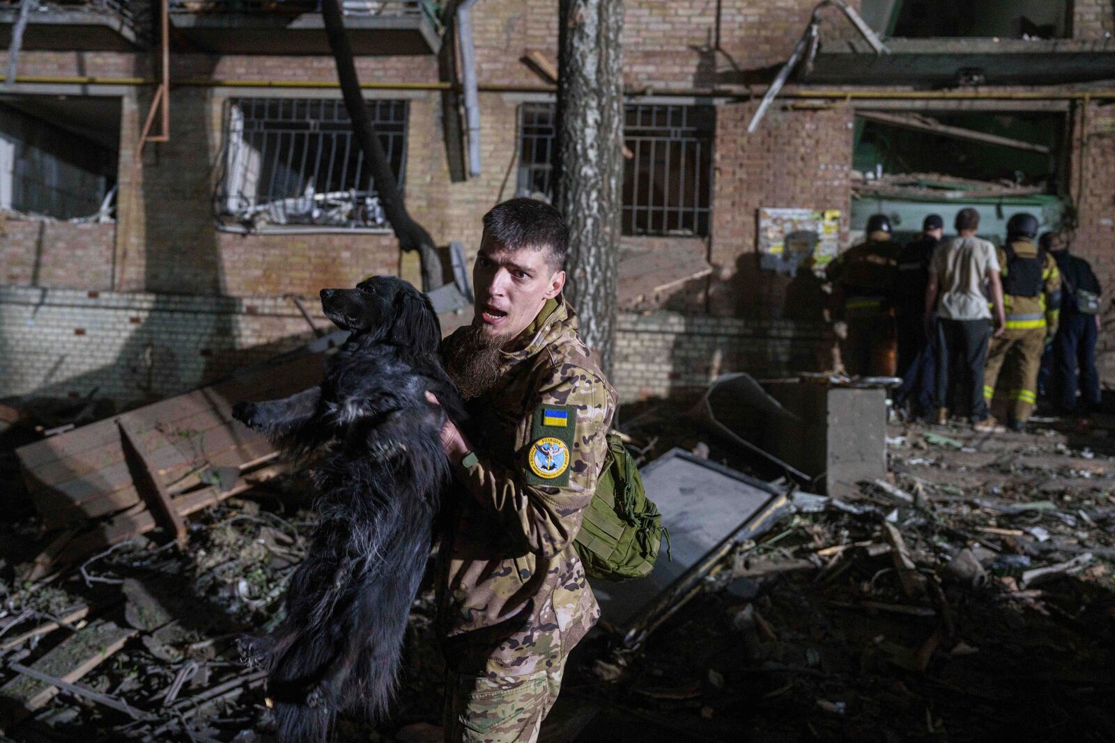 A Ukrainian serviceman carries a dog out of a house damaged by a Russian airstrike in a residential neighborhood in Kyiv, Ukraine, on Thursday, April 24, 2025. (AP Photo/Evgeniy Maloletka)