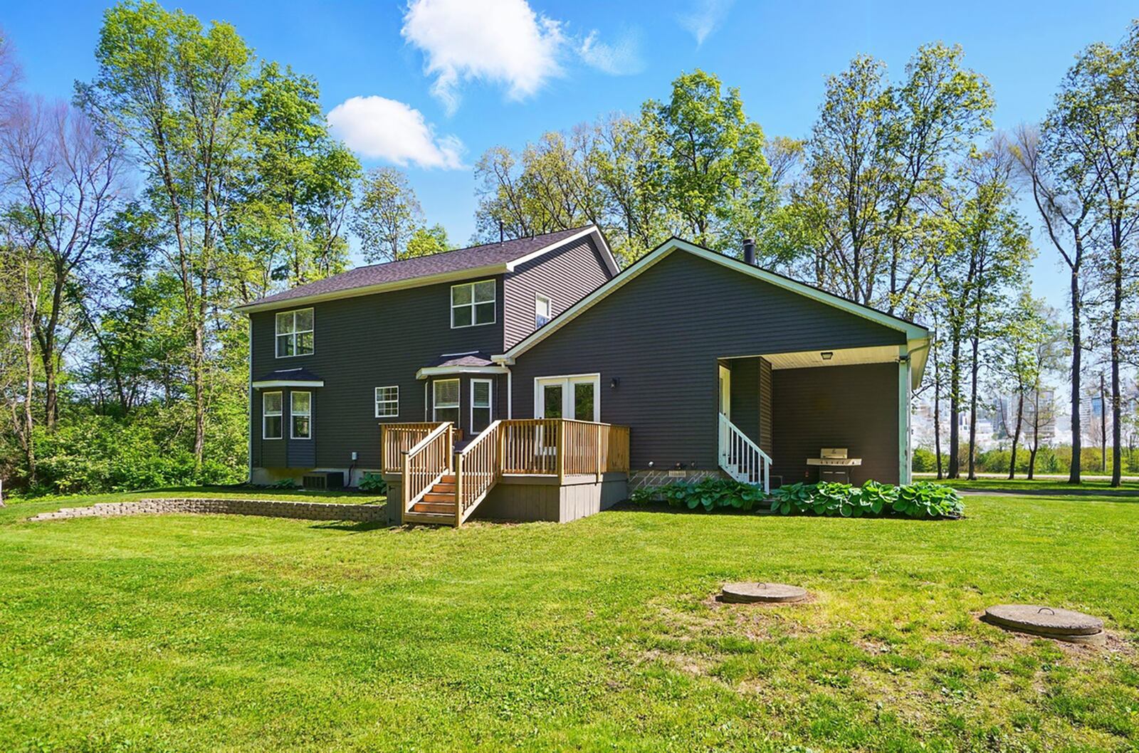The rear of the home features a wood deck with railings and a separate covered concrete porch off the family room.