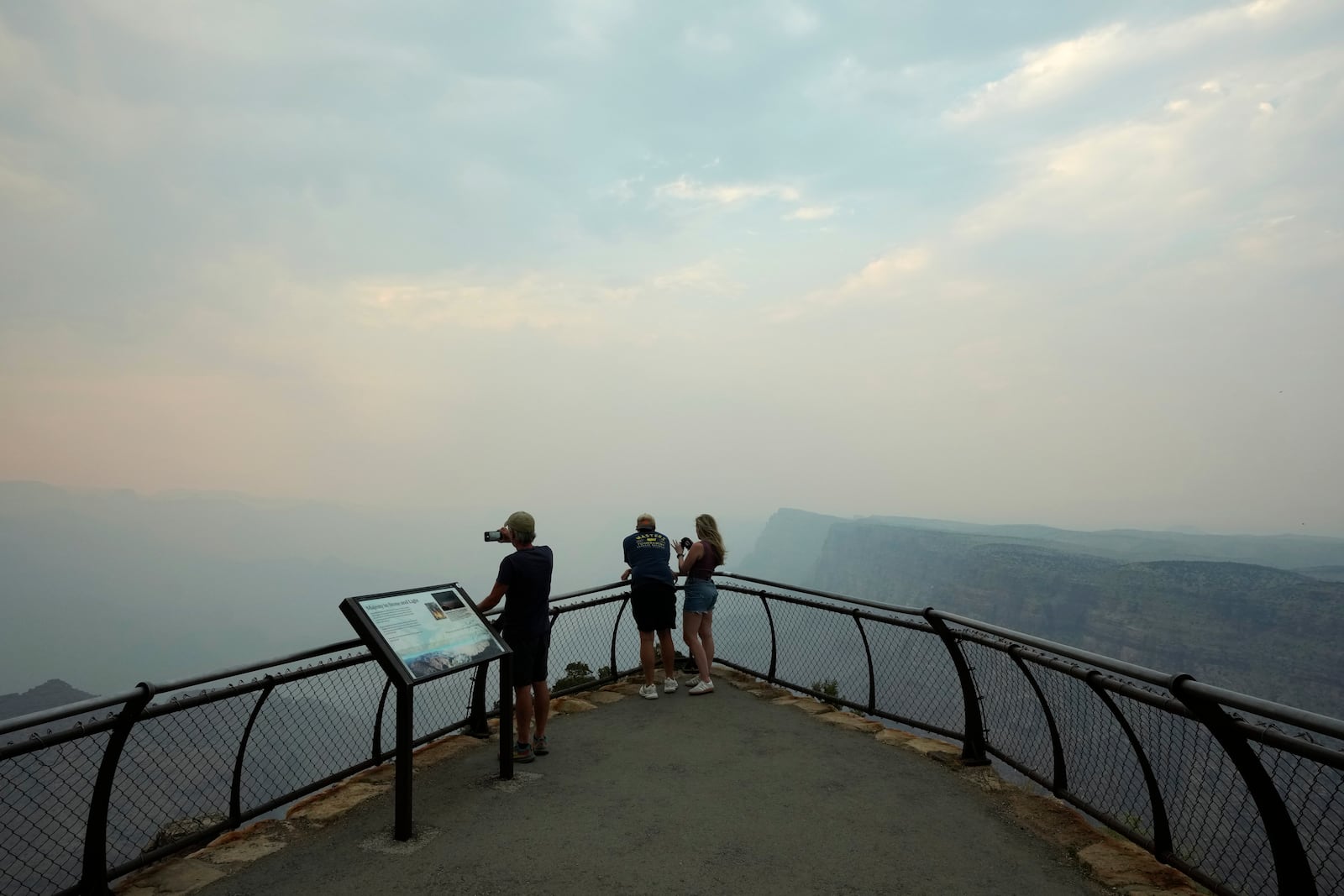 Smoke from the Dragon Bravo Fire moves over the Grand Canyon from the North Rim blocking the view for tourists at the Desert View overlook Monday, July 14, 2025, in Grand Canyon National Park, Ariz. (AP Photo/Ross D. Franklin)
