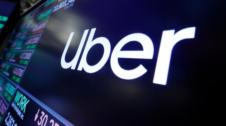 FILE - The Uber logo appears above a trading post on the floor of the New York Stock Exchange, Aug. 16, 2019. (AP Photo/Richard Drew, File)