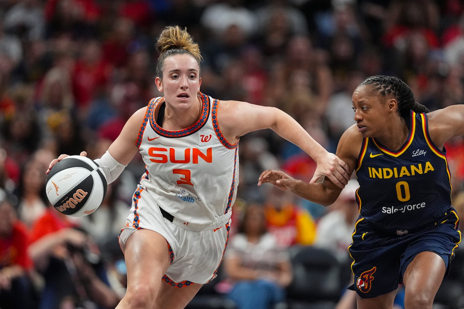 Connecticut Sun guard Marina Mabrey (3) drives on Indiana Fever guard Kelsey Mitchell (0) in the first half of a WNBA basketball game in Indianapolis, Tuesday, June 17, 2025. (AP Photo/Michael Conroy)