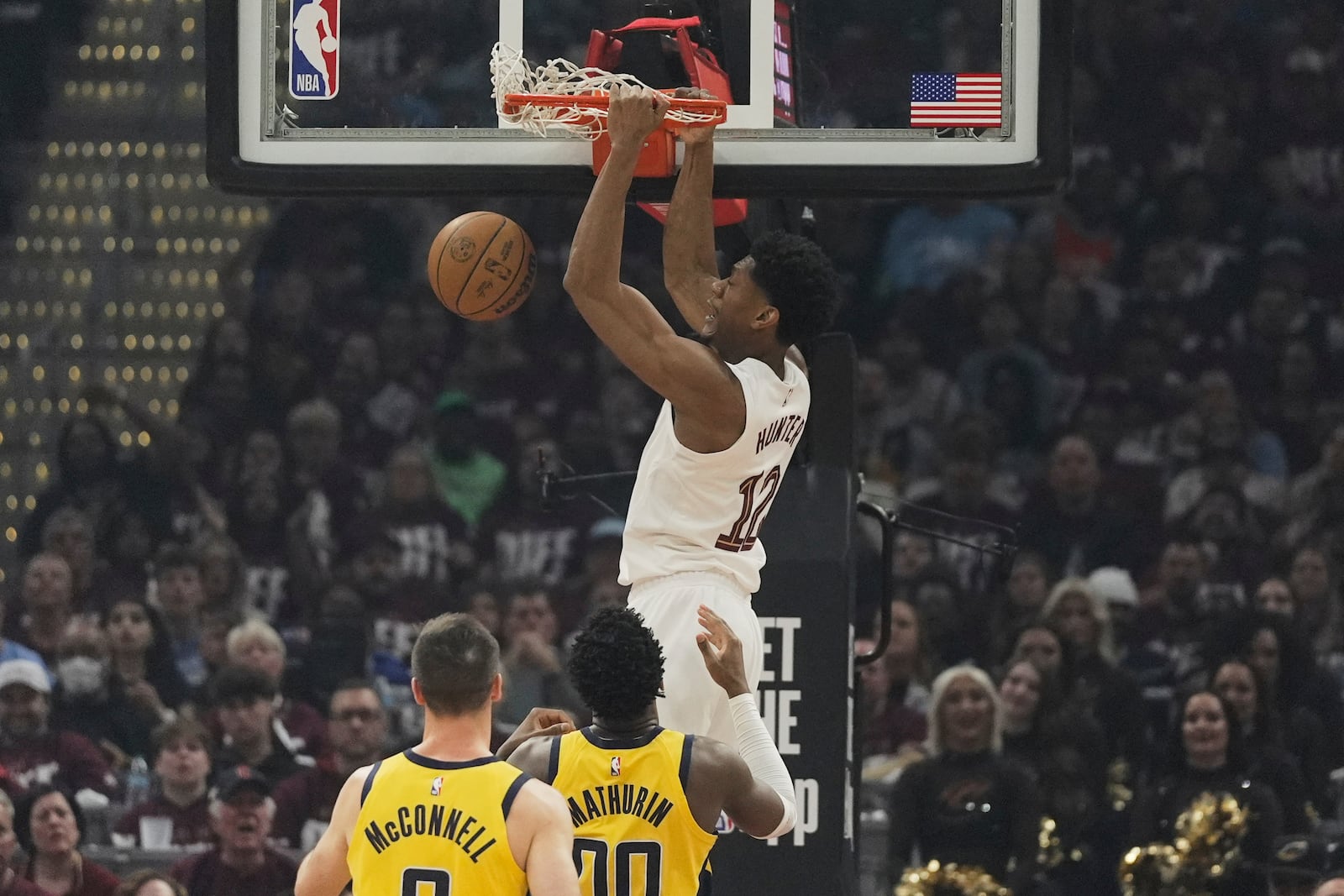 Cleveland Cavaliers forward De'Andre Hunter, top, dunks over Indiana Pacers guards T.J. McConnell, left, and Bennedict Mathurin (00) in the first half during Game 1 in the Eastern Conference semifinals of the NBA basketball playoffs Sunday, May 4, 2025, in Cleveland. (AP Photo/Sue Ogrocki)