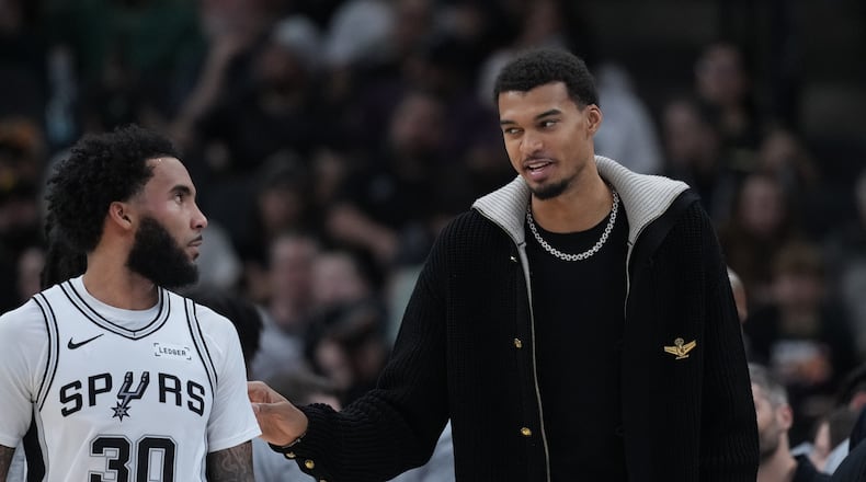 San Antonio Spurs forward Victor Wembanyama, right, talks with teamamte forward Julian Champagnie (30) during the first half of an NBA basketball game against the Sacramento Kings in San Antonio, Sunday, Nov. 16, 2025. (AP Photo/Eric Gay)
