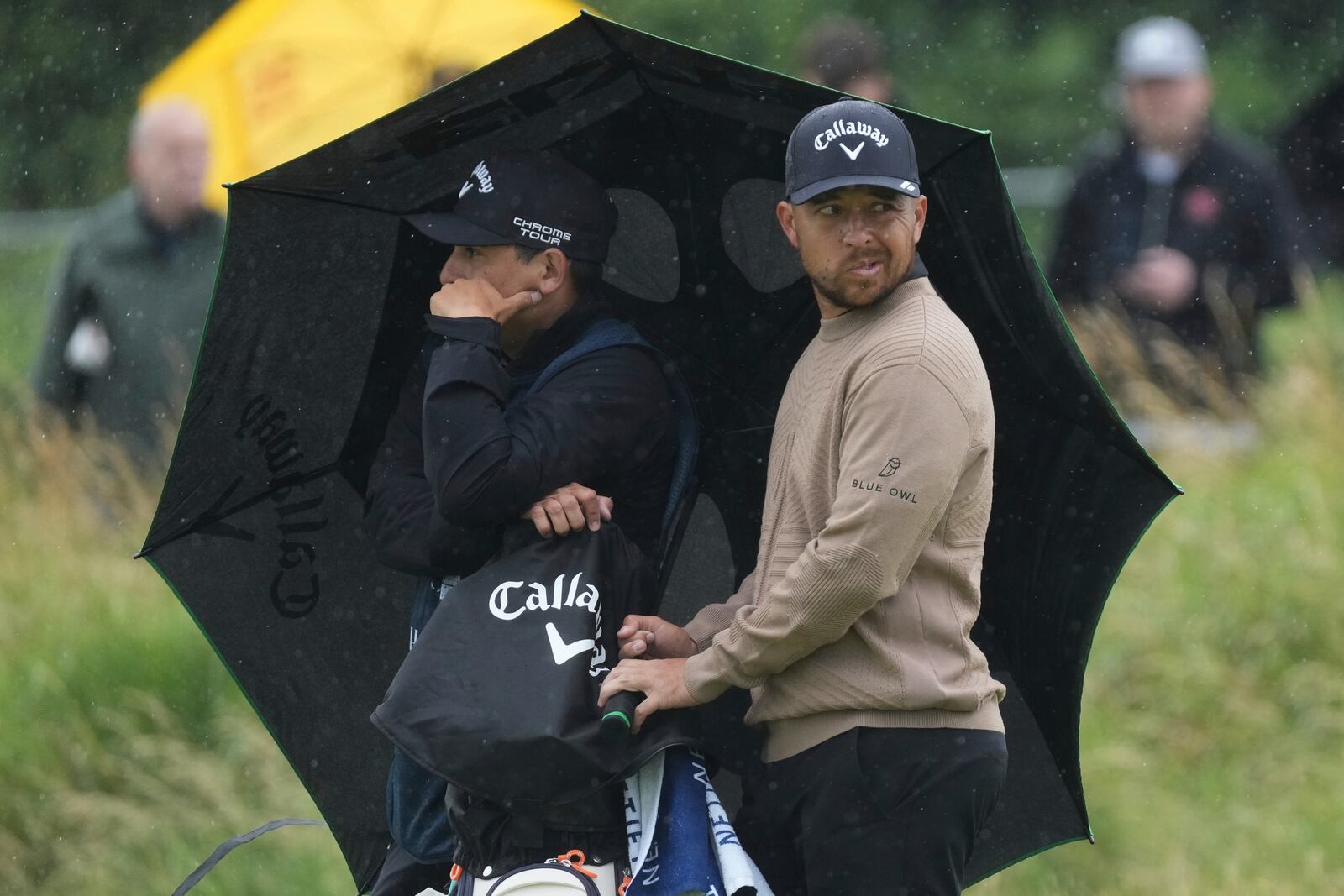 Xander Schauffele of the United States looks round as he shelters under an umbrella on the 2nd hole during the first round of the British Open golf championship at the Royal Portrush Golf Club, Northern Ireland, Thursday, July 17, 2025. (AP Photo/Jon Super)