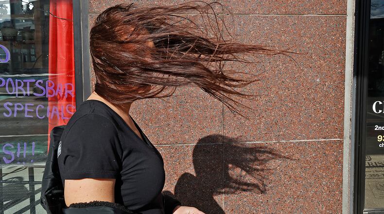 Tish Molina's face is obscured by her hair as it blows in the wind Thursday, Feb. 9, 2023 as she walks along Main Street in Springfield. Wind gusts were measured up to 60 mph in the region Thursday. BILL LACKEY/STAFF