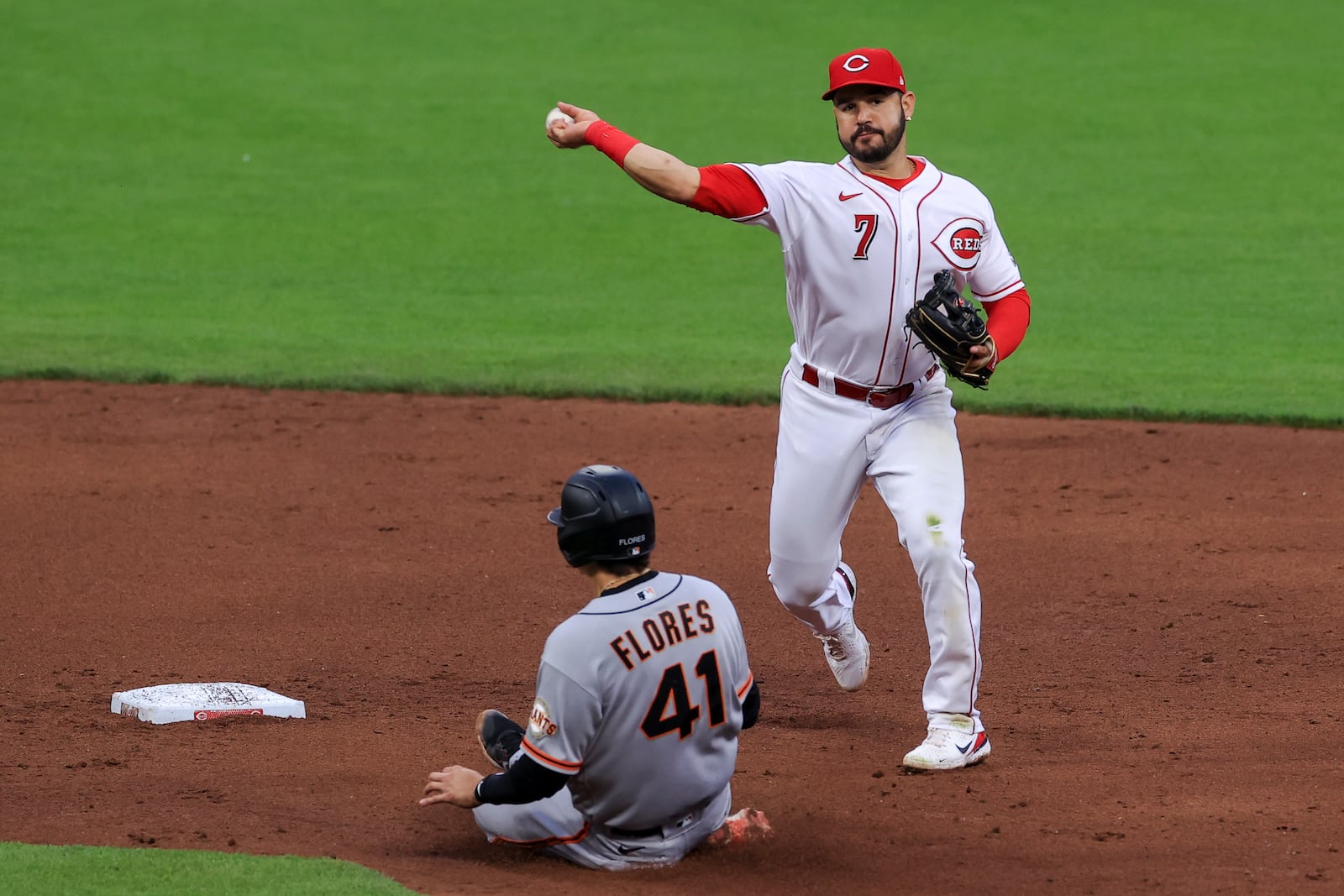 San Francisco Giants' Wilmer Flores, left, is forced out at second base as Cincinnati Reds' Eugenio Suarez (7) throws to first base to turn a double play during the sixth inning of a baseball game in Cincinnati, Monday, May 17, 2021. Giants' Alex Dickerson was out at first base on the play. (AP Photo/Aaron Doster)
