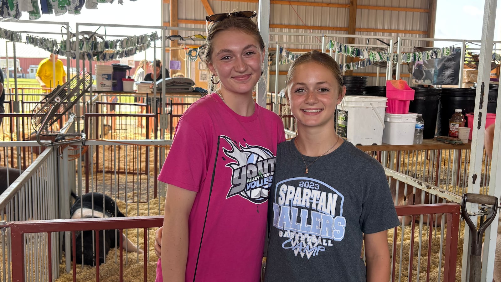Lucy Shell (left) and Liberty Shell (right) stand in front of a pig pen at the Montgomery County Fair Market Hog Weigh-In on Monday, July 7, 2025. GRAETER / STAFF