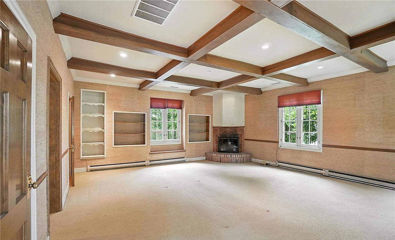 The first floor family room could also be a primary suite with a full bathroom. It has built in shelving and a corner woodburning fireplace.