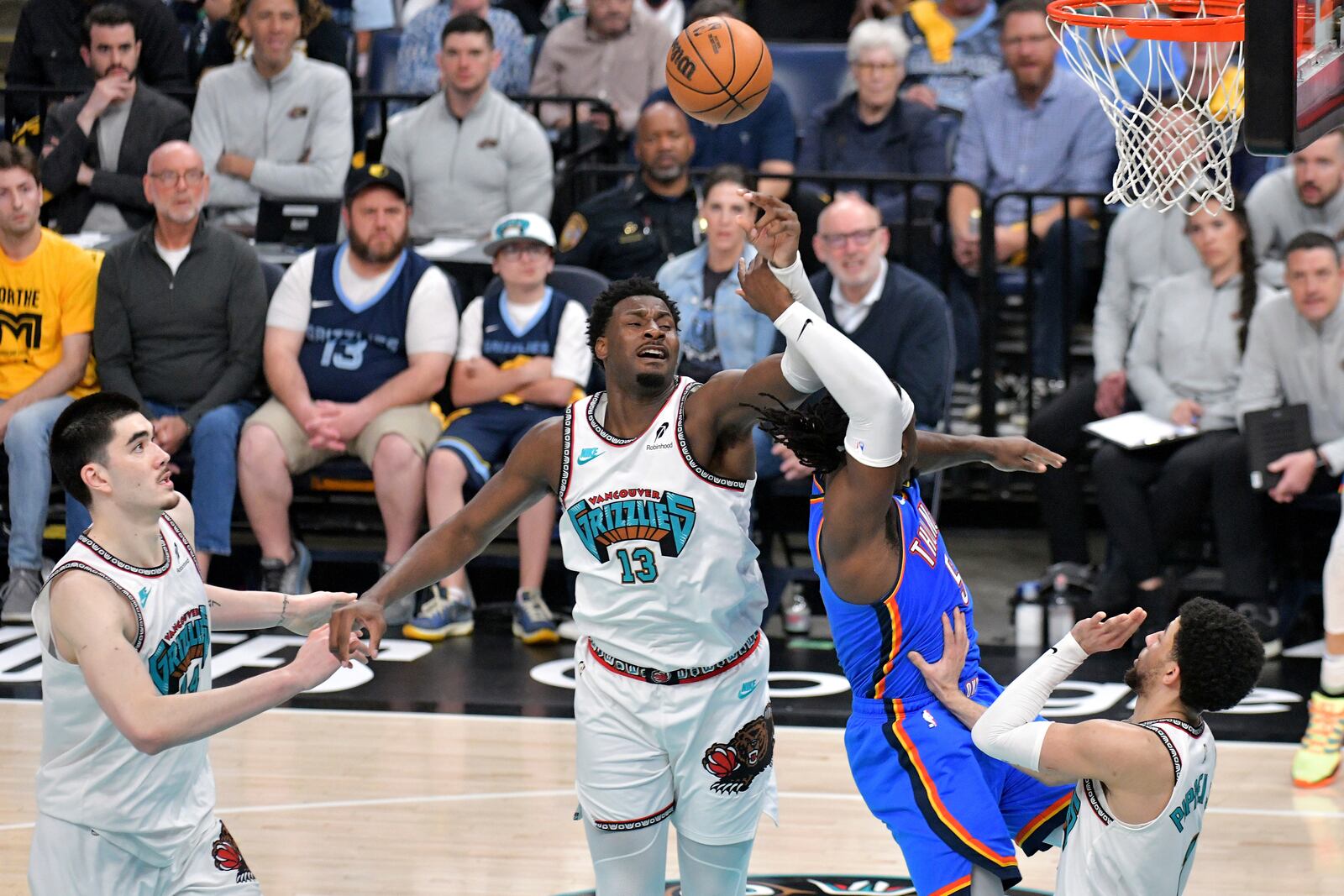 Oklahoma City Thunder guard Luguentz Dort (5) shoots against Memphis Grizzlies forward Jaren Jackson Jr. (13) and guard Scotty Pippen Jr. (1) as center Zach Edey (14) moves for position in the second half of Game 3 of an NBA first-round playoff series Thursday, April 24, 2025, in Memphis, Tenn. (AP Photo/Brandon Dill)