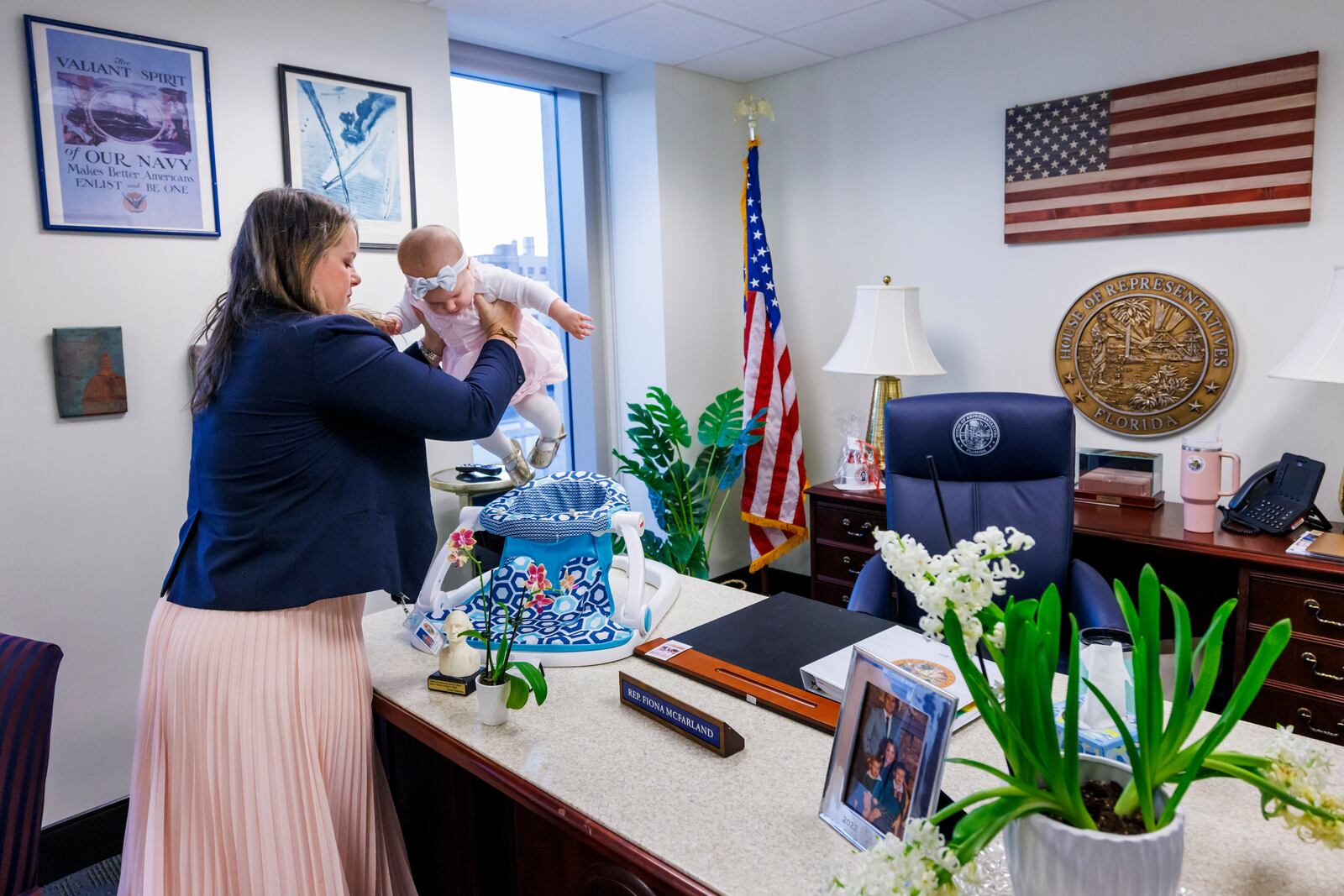 Florida Rep. Fiona McFarland, R-Sarasota, lifts her 7-month-old daughter Grace Melton into a chair on her desk as she starts her work day at the state Capitol, Thursday, April 17, 2025, in Tallahassee, Fla. (AP Photo/Colin Hackley)
