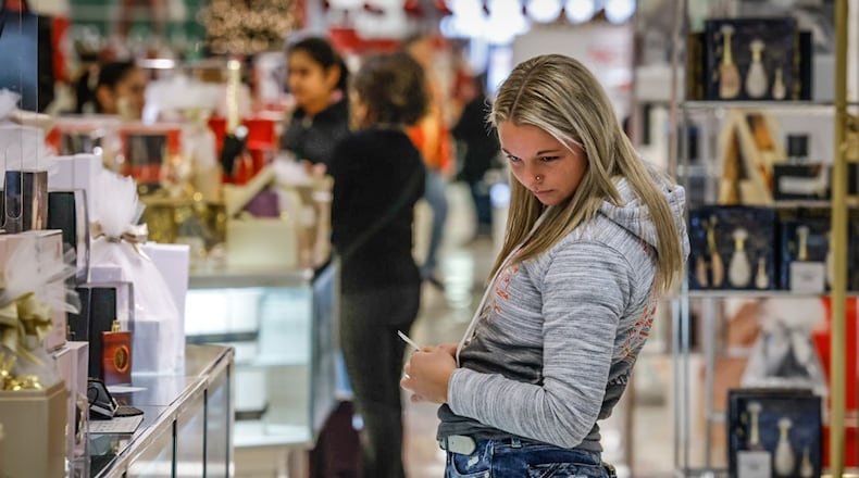 A shopper in Macy's at the Dayton Mall peruses the fragrance section of the store Wednesday December 21, 2022. The Dayton Mall was busy with Christmas just days away and online shipping deadlines passed. JIM NOELKER/STAFF