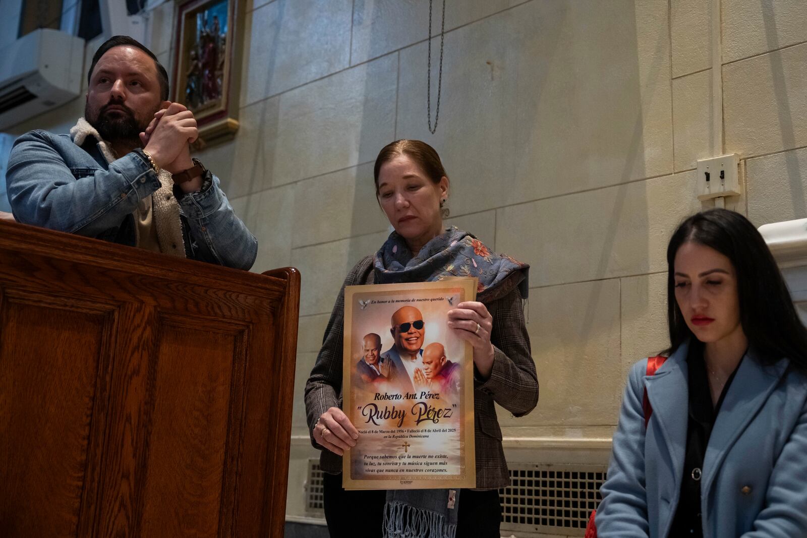 People attend a Mass, holding an image of Rubby Perez, for the victims of the Jet Set club roof collapse, at St. Elizabeth's Church, Wednesday, April 9, 2025 in New York. (AP Photo/Adam Gray)