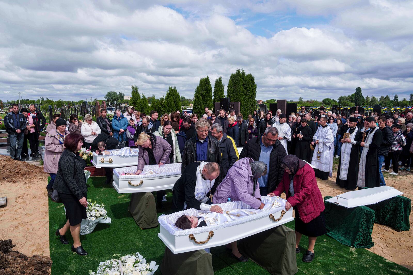 Relatives say goodbye to children Roman Martyniuk, 17, Tamara Martyniuk, 8, and Stanislav Martyniuk, 12, killed in a Russian strike on Sunday, during farewell ceremony in Korostyshiv, Zhytomyr region, Ukraine, Wednesday, May 28, 2025. (AP Photo/Evgeniy Maloletka)