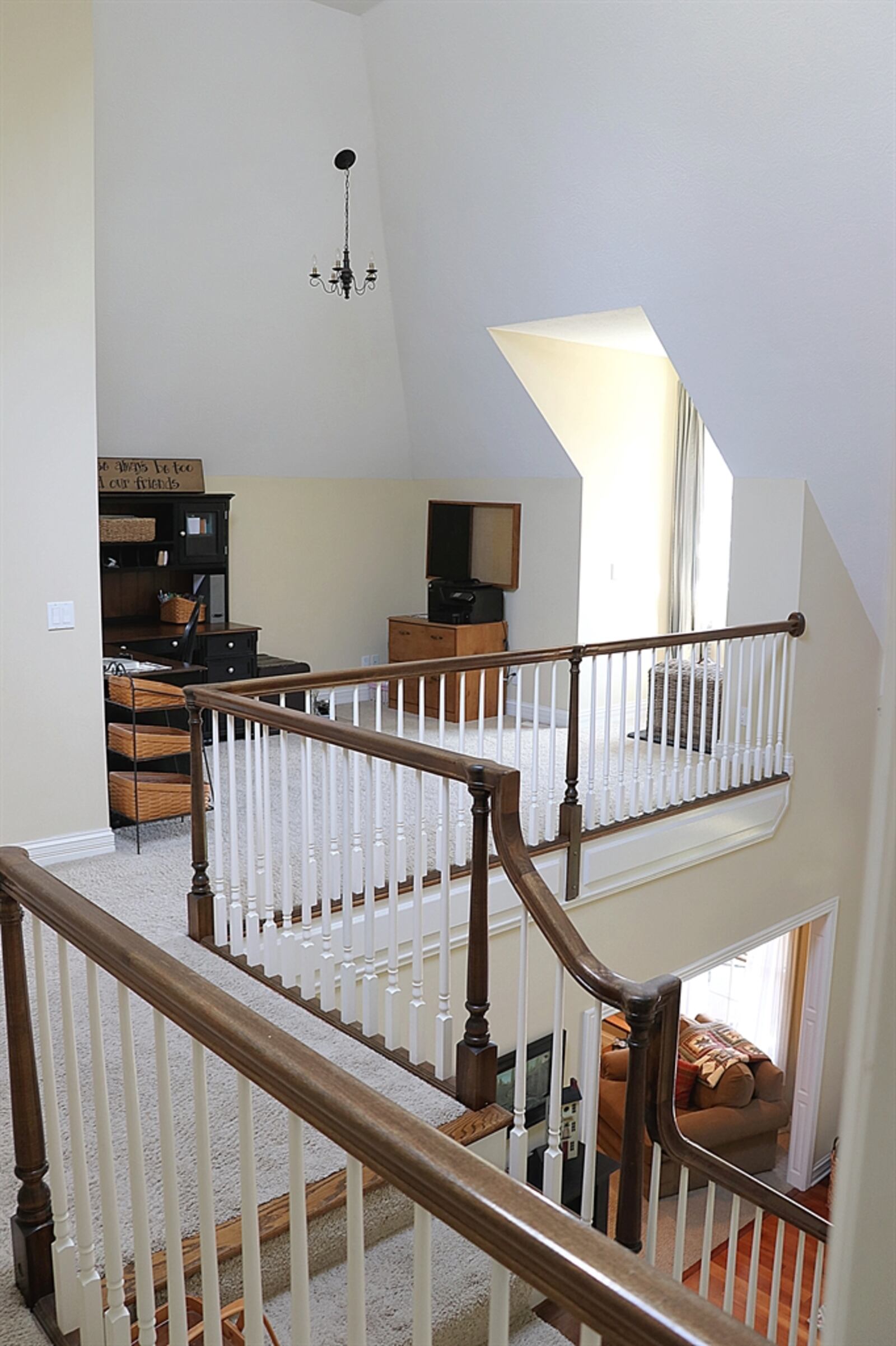 The two-story foyer has a spindled railing that accents the open staircase and wraps up to the balcony hallway and loft study.