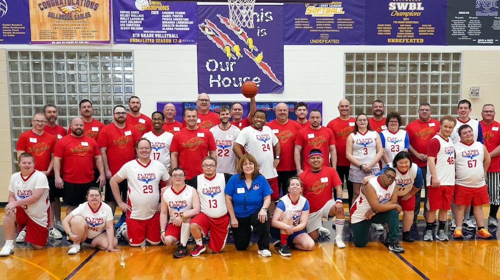 The Flying Eagles (in white) and the Extinguishers (in red) gathered for a group photo before their “Super Bowl” encounter on Monday, Feb. 23, 2026 at the Bellbrook Junior High gym. Gayle Horton, the director of Colin’s Lodge, whose members make up the Eagles, is in the center (in blue). Sugarcreek Township Fire Marshal Jordan Ewing who helped launch the idea of the game six years ago when he got together the Extinguishers, who are Sugarcreek Township and Bellbrook firefighters, EMS and police, is fifth from the left in row two. BELLBROOK LOCAL SCHOOLS / CONTRIBUTED PHOTO