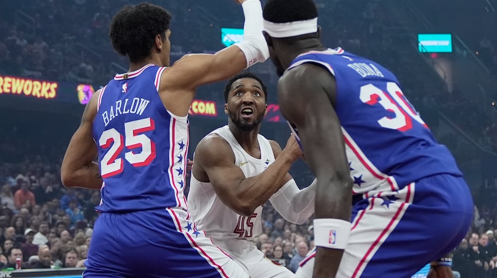 Cleveland Cavaliers guard Donovan Mitchell, center, eyes the basket between Philadelphia 76ers forward Dominick Barlow (25) and center Adem Bona (30) in the first half of an NBA basketball game in Cleveland, Monday, March 9, 2026. (AP Photo/Sue Ogrocki)