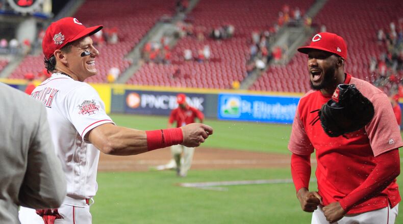 Derek Dietrich, left, reacts after Amir Garrett dumped a bucket of Powerade on him after a victory against the Pirates on Tuesday, May 28, 2019, at Great American Ball Park in Cincinnati. David Jablonski/Staff