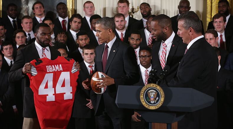 WASHINGTON, DC - APRIL 20: Doran Grant (L) of the Ohio State University Buckyes football team presents U.S. President Barack Obama (2nd L) a team jersey as teammate Curtis Grant (3rd L) and head coach Urban Meyer (R) look on during an East Room event at the White House April 20, 2015 in Washington, DC. President Obama hosted the football team to honor its victory on the first ever College Football Playoff National Championship. (Photo by Alex Wong/Getty Images)
