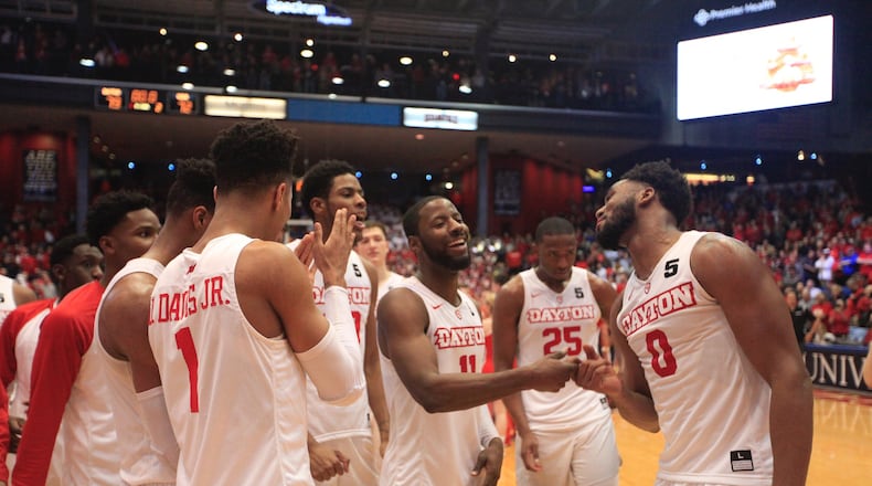 Dayton’s Scoochie Smith, center, and Josh Cunningham right, celebrate with teammates after a victory against Virginia Commonwealth on Wednesday, March 1, 2017, at UD Arena. David Jablonski/Staff