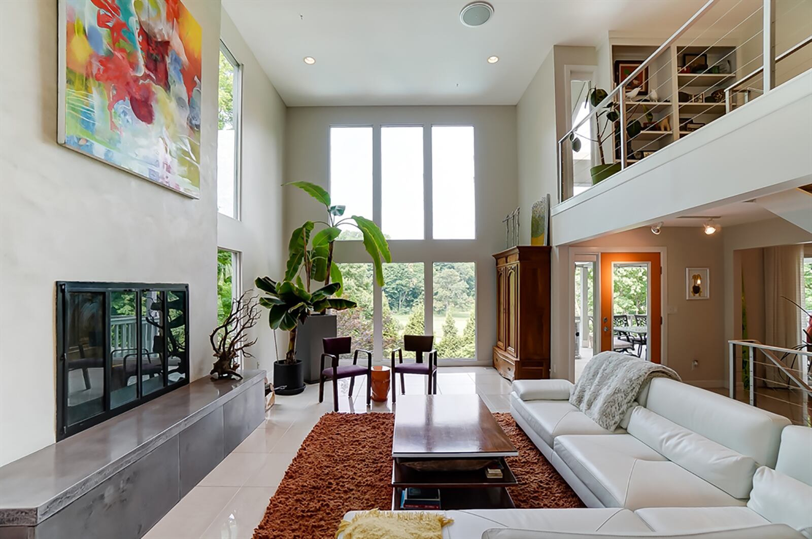 Outdoor views can be enjoyed from the 2-story great room with a Venetian plaster fireplace that has a polished concrete hearth. A stainless-steel banister with horizontal cables continues the clean lines within the open staircase that leads to the second and lower levels. CONTRIBUTED PHOTO