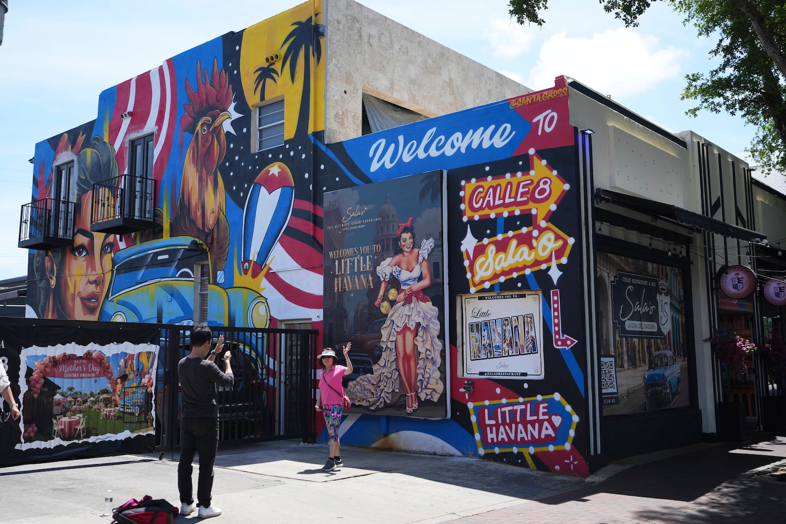 People take photographs next to a mural featuring a rooster on Calle Ocho in the Little Havana neighborhood of Miami, Wednesday, May 7, 2025. (AP Photo/Lynne Sladky)