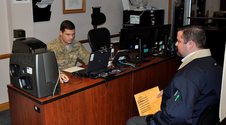 Staff Sgt. Eric Duke logs in information from customer Sargent Engle IV for a restricted area/controlled area badge at the 88th Security Forces Pass and Registration office in Area A, Bldg. 286. (U.S. Air Force photo/W. Eugene Barnett)