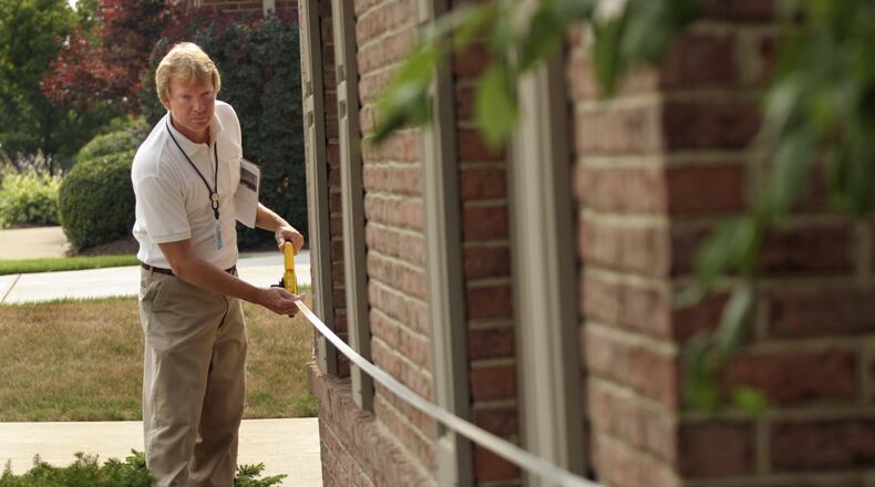 Tom Schoemaker, a Montgomery County Data Collector, takes a measurement on an exterior wall to verify the accuracy of the dimensions on the property record card in the Savina Hill Estates neighborhood. FILE