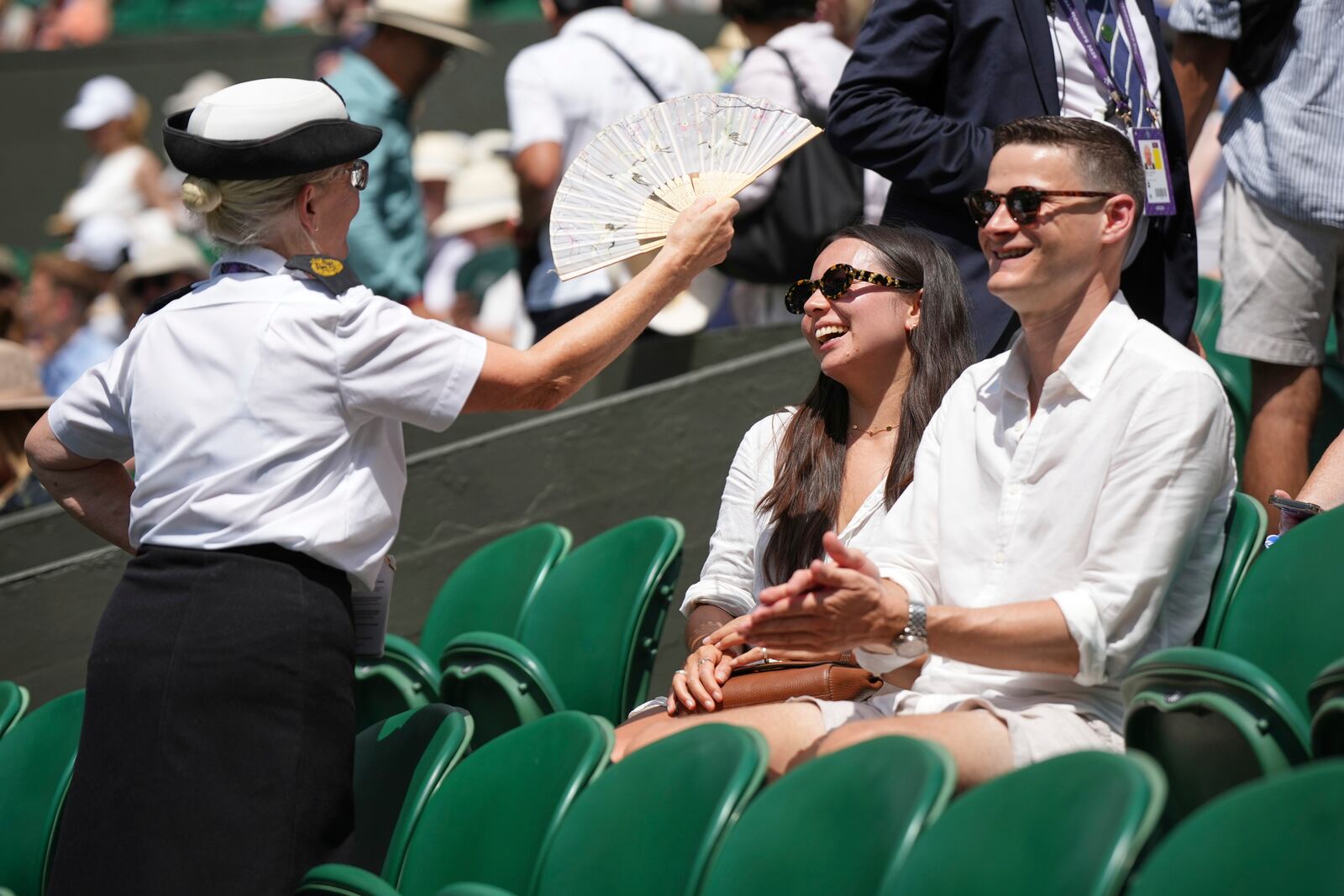 A steward fans spectators sitting on Centre Court on day one of the Wimbledon Tennis Championships in London, Monday, June 30, 2025. (AP Photo/Alastair Grant)