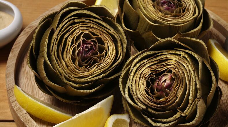 Artichokes steam in a lemon-, garlic- and bay leaf-scented bath until tender. A tahini dip for dunking brings more lemon and garlic to the dish. (E. Jason Wambsgans/Chicago Tribune/TNS)
