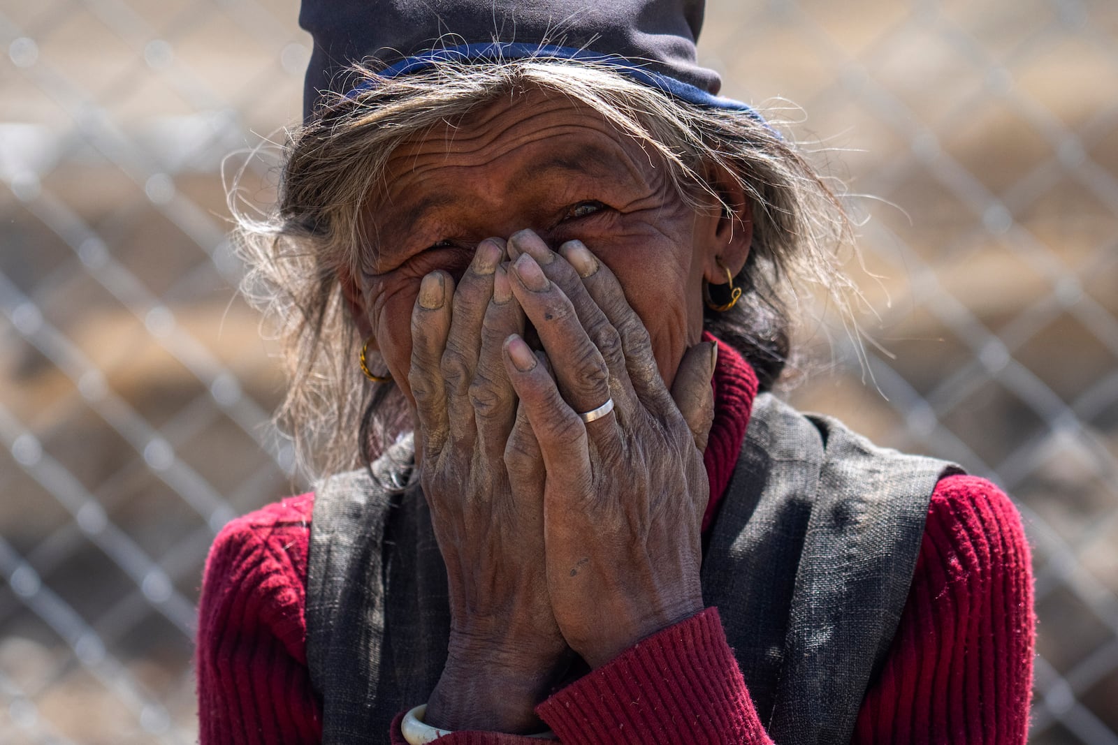 An elderly woman reacts while being photographed at the newly relocated settlement of the abandoned Samjungvillage in the Mustang region, 462 kilometers (288 miles) west of Kathmandu, Nepal, Friday, April 18, 2025. (AP Photo/Niranjan Shrestha)