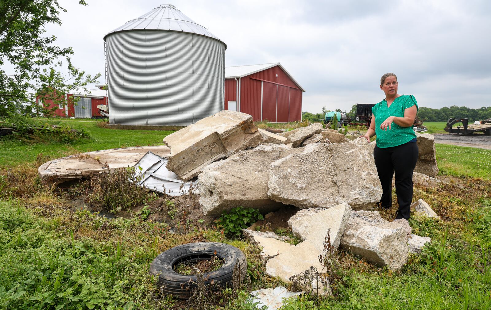 Jennifer Vollmer talks about tornado damage her property sustained while standing in front of the remains of a silo that was destroyed during the storm last year. BRYANT BILLING / STAFF