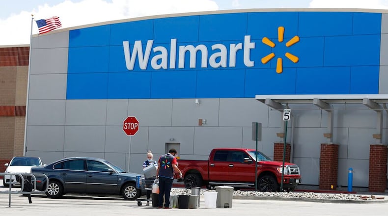 FILE PHOTO: Workers sanitize items outside a Walmart. Workers will be getting another bonus from the company.