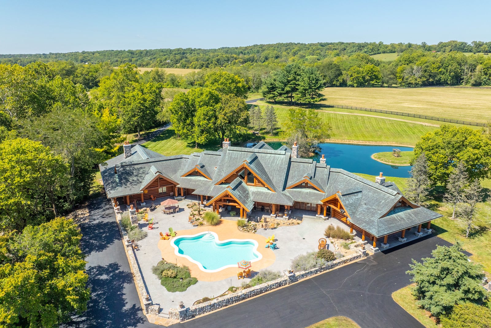 An inground pool with fiber optic lighting is the centerpiece of a stamped concrete courtyard in back of the 7,000-square foot custom log home with a copper roof on an equestrian estate up for auction in Warren County. CONTRIBUTED