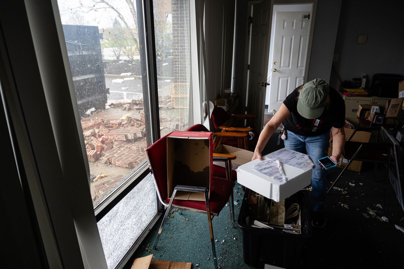 Lisa Davis reviews paperwork in a business that was damaged in the Triad Building, a business plaza, after severe weather passed through Thursday, April 3, 2025, in Louisville, Ky. (AP Photo/Jon Cherry)