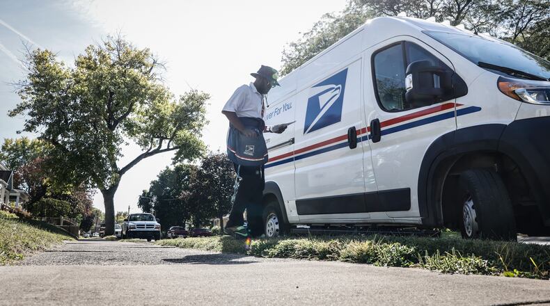 A mail carrier walks back to his truck after picking up and delivering mail on the eastside of Dayton. JIM NOELKER/STAFF