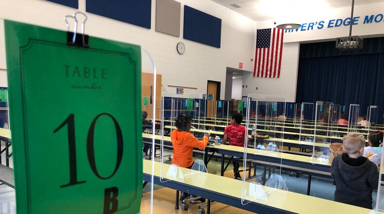 Students eat lunch at Dayton's River's Edge Montessori School during November, sitting far apart, with plexiglass dividers between them. CONTRIBUTED PHOTO