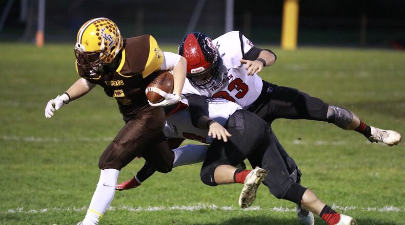 Kenton Ridge’s Zach Schneider gets knocked out of bounds by Tecumseh s Ryan Rowland and Caleb Edwards as he carries the ball. Bill Lackey/Staff