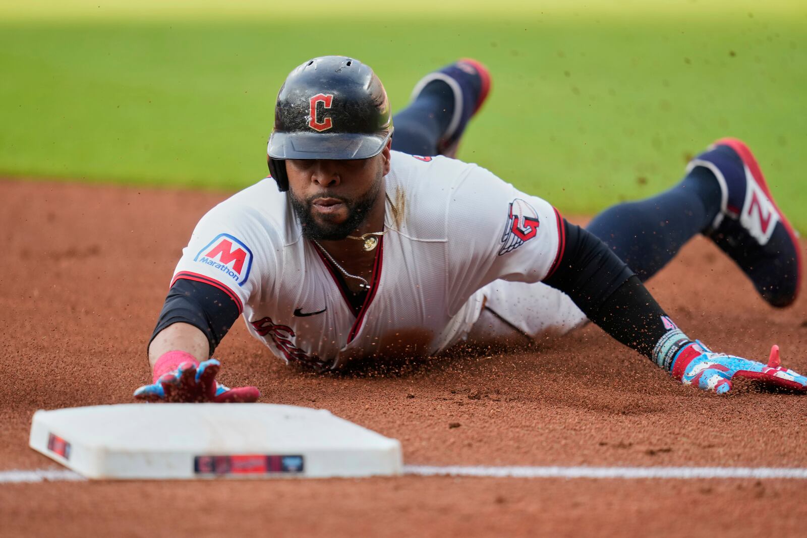 Cleveland Guardians' Carlos Santana slides safely into third base on a hit by Lane Thomas in the first inning of a baseball game against the Detroit Tigers in Cleveland, Friday, July 4, 2025. (AP Photo/Sue Ogrocki)