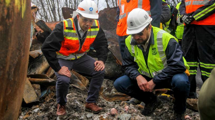 Transportation Secretary Pete Buttigieg, left, and Tristan Brown, deputy administrator of the Pipeline and Hazardous Materials Safety Administration, crouch down to look at part of a burned traincar, Thursday, Feb. 23, 2023, in East Palestine, Ohio, at the site of a Norfolk Southern train derailment. (Allie Vugrincic/The Vindicator via AP, Pool)