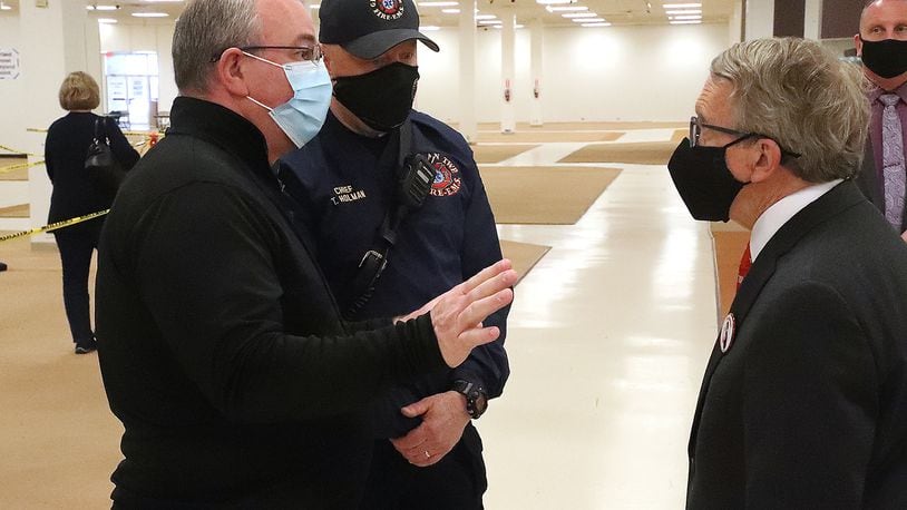 German Township Fire Chief Tim Holman and Clark County Health Commissioner Charles Patterson talk to Governor Mike DeWine during the governor's recent stop at the COVID vaccine distribution center in Clark County. BILL LACKEY/STAFF