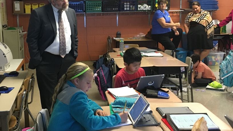 State school superintendent Paolo DeMaria (standing, left) watches students at Shaw Elementary in Beavercreek work on a math activity that was integrated with their PAX behavior program last month. JEREMY P. KELLEY/STAFF